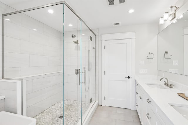 full bath with double vanity, a stall shower, visible vents, tile patterned flooring, and a sink