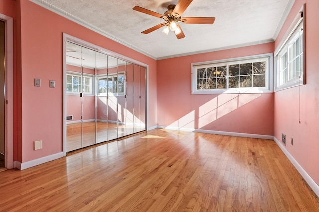 unfurnished room with hardwood / wood-style flooring, a textured ceiling, baseboards, and crown molding