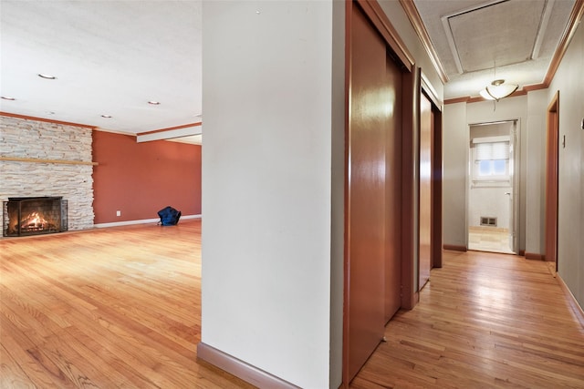 hall with visible vents, attic access, ornamental molding, light wood-type flooring, and baseboards