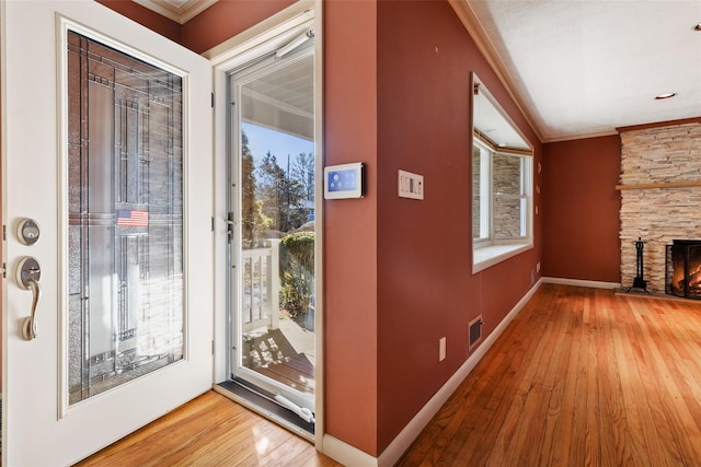 entryway featuring ornamental molding, a fireplace, wood finished floors, and baseboards