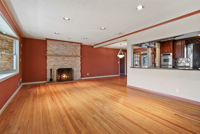 unfurnished living room featuring light wood finished floors, a fireplace, baseboards, and crown molding