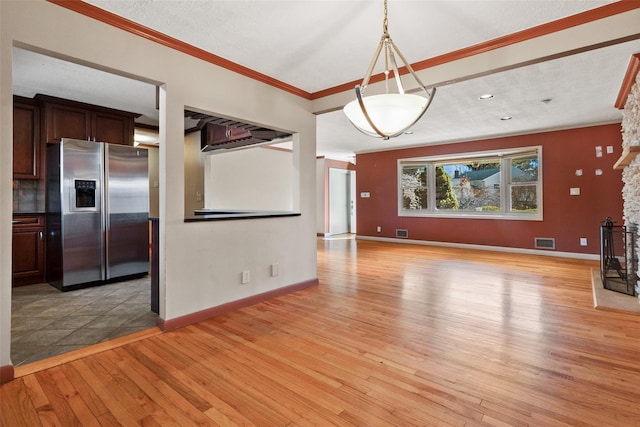 unfurnished living room with baseboards, visible vents, crown molding, light wood-type flooring, and a fireplace