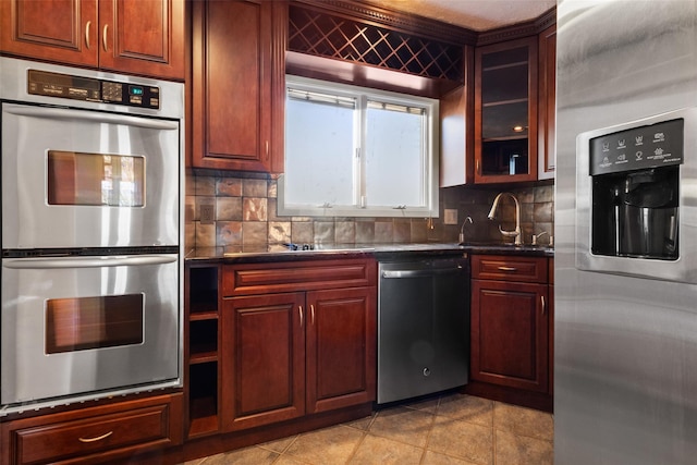 kitchen featuring appliances with stainless steel finishes, dark countertops, a sink, and tasteful backsplash