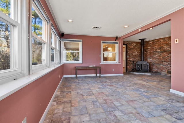 unfurnished sunroom featuring a wood stove and visible vents