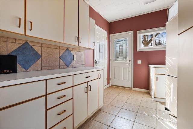 kitchen with light tile patterned flooring, baseboards, white cabinets, light countertops, and backsplash