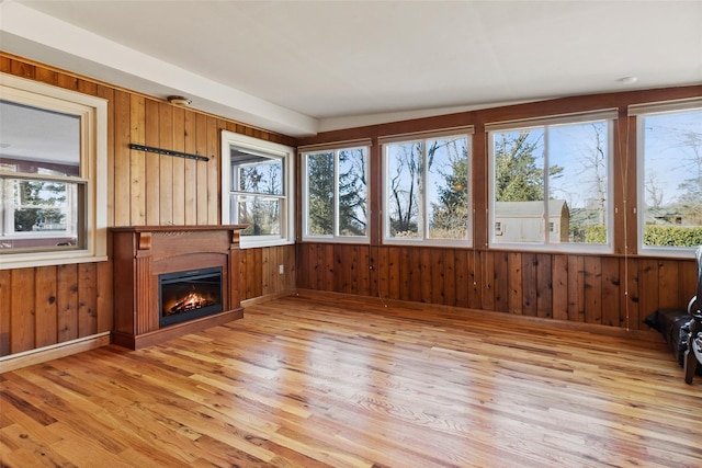 unfurnished living room featuring a glass covered fireplace, plenty of natural light, and light wood-style flooring