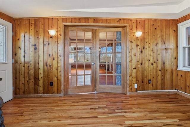 doorway with wooden walls, baseboards, wood finished floors, and french doors