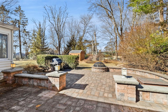 view of patio with an outdoor fire pit, a shed, and an outdoor structure