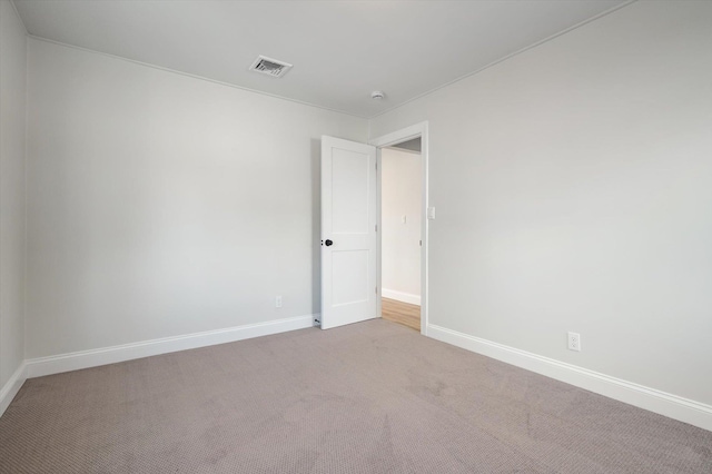 empty room featuring light colored carpet, visible vents, and baseboards