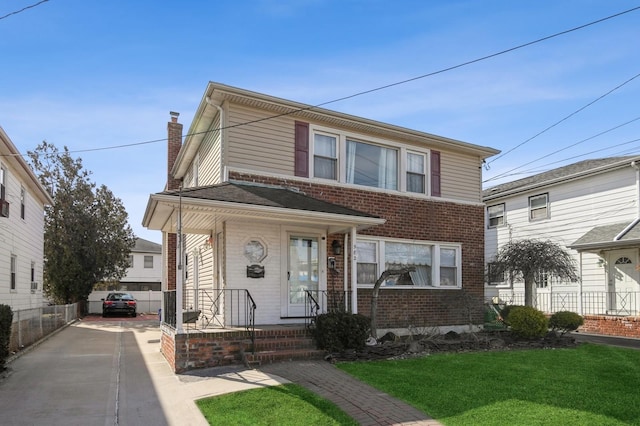 view of front of house featuring brick siding, a chimney, fence, driveway, and a front lawn