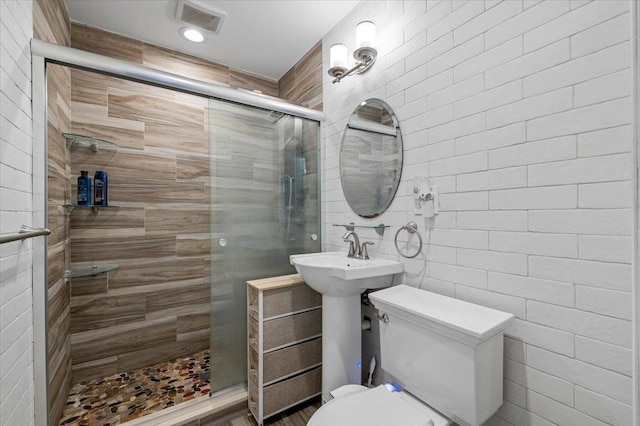 bathroom with toilet, tile walls, visible vents, and tiled shower