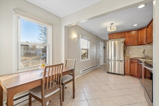 kitchen featuring brown cabinets, baseboard heating, stainless steel appliances, and a sink