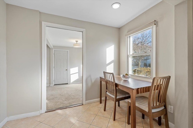 dining area featuring light tile patterned floors, baseboards, and light colored carpet