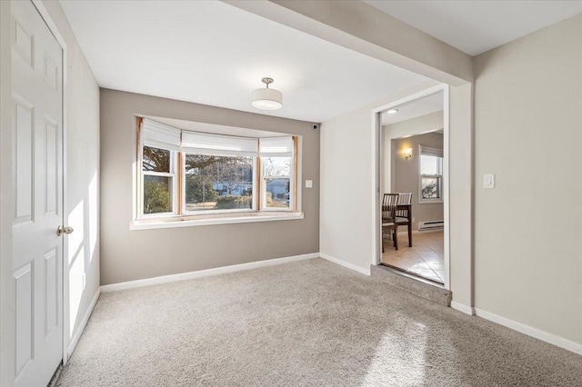 carpeted empty room featuring baseboard heating and baseboards