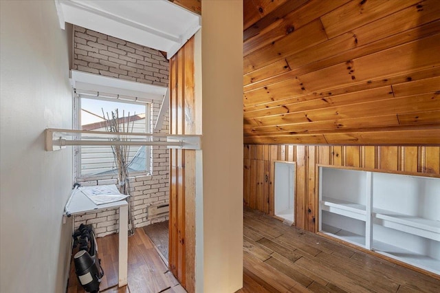 corridor featuring brick wall and hardwood / wood-style flooring