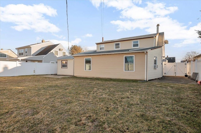 back of property featuring a gate, a fenced backyard, and a lawn