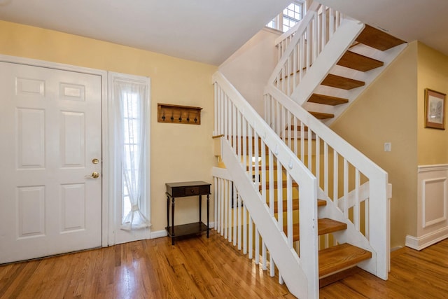 foyer featuring baseboards, stairway, and wood finished floors