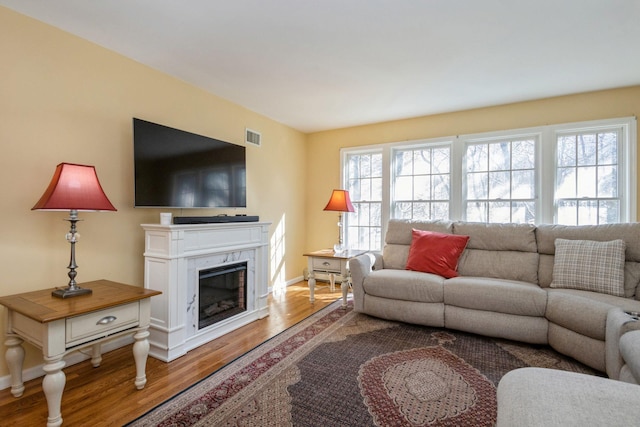 living room with baseboards, a fireplace, visible vents, and wood finished floors