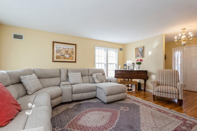 living area with a chandelier, visible vents, baseboards, and wood finished floors