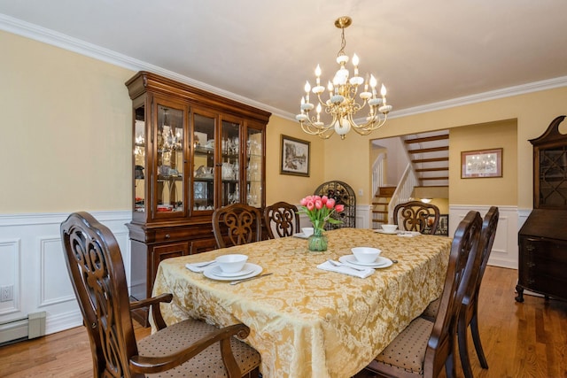 dining space with a wainscoted wall, stairway, and wood finished floors