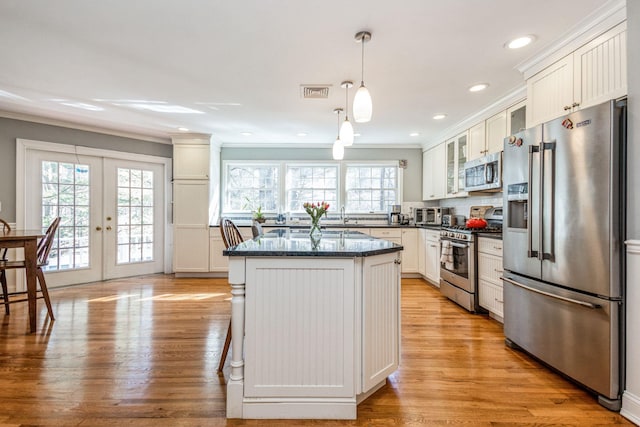 kitchen featuring stainless steel appliances, visible vents, french doors, a center island, and glass insert cabinets