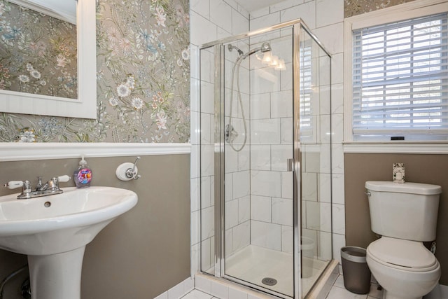 full bathroom featuring toilet, wallpapered walls, and a stall shower