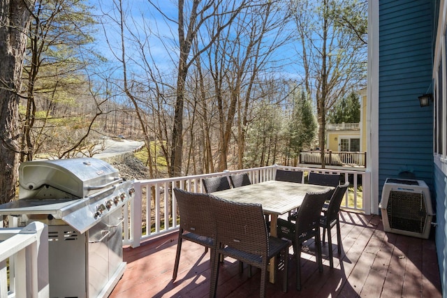 wooden terrace with a grill and outdoor dining space