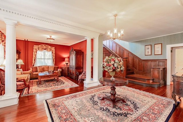 living area with a chandelier, hardwood / wood-style flooring, stairway, decorative columns, and crown molding