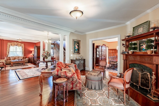 living room featuring crown molding, a high end fireplace, stairs, wood-type flooring, and ornate columns