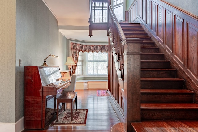 staircase featuring wallpapered walls, wood finished floors, and crown molding