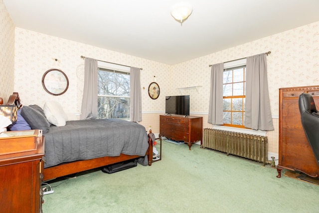 carpeted bedroom with wallpapered walls, radiator heating unit, multiple windows, and wainscoting