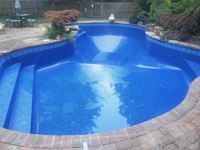 view of swimming pool with a diving board, a patio area, fence, and a fenced in pool