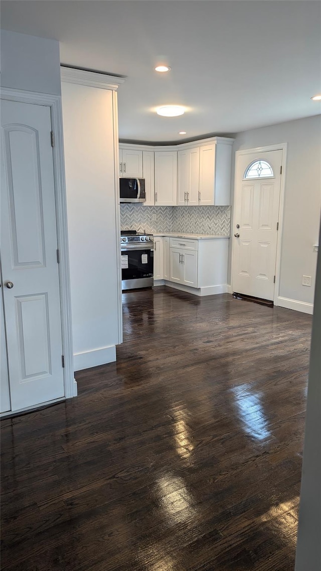 kitchen with appliances with stainless steel finishes, dark wood-style flooring, white cabinets, and tasteful backsplash