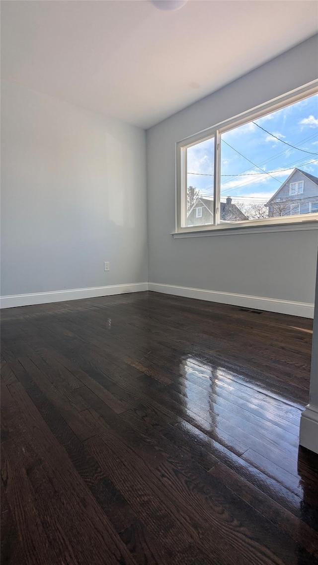 spare room with visible vents, dark wood finished floors, and baseboards