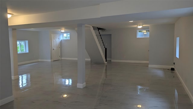 below grade area featuring marble finish floor, baseboards, and stairs