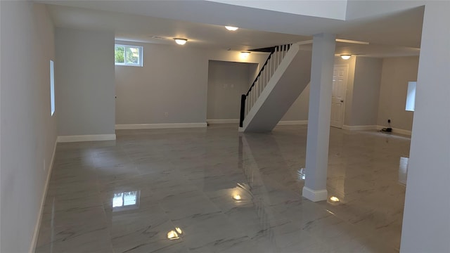 below grade area with marble finish floor, baseboards, and stairs