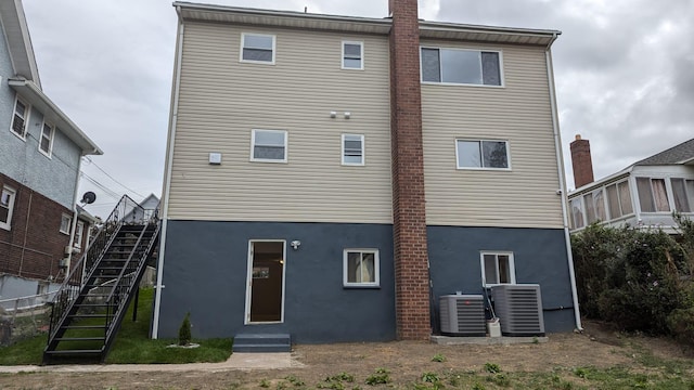 back of house with stairs, stucco siding, and central air condition unit