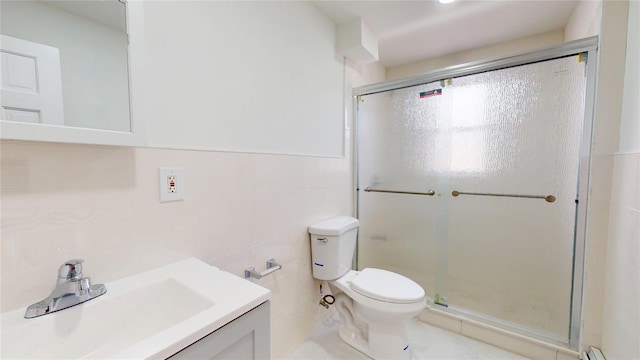 bathroom with toilet, a stall shower, vanity, and tile walls