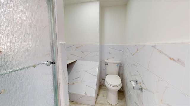 bathroom with wainscoting, tile walls, and toilet