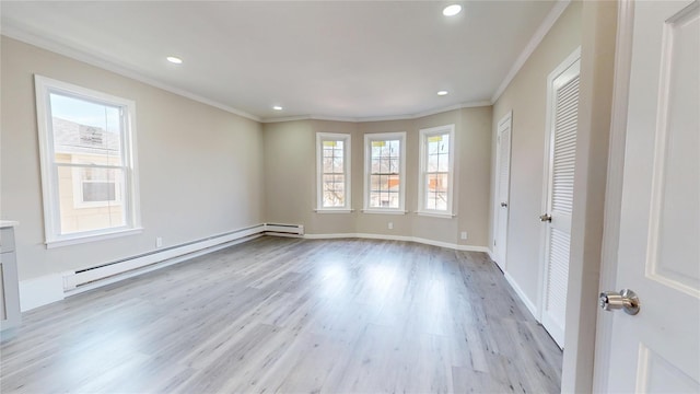 empty room featuring a baseboard heating unit, a healthy amount of sunlight, light wood-style floors, and crown molding