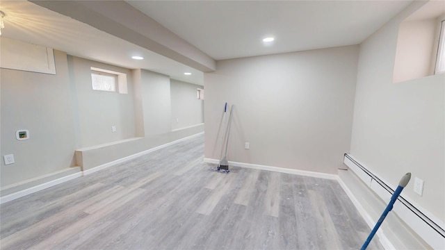 below grade area featuring a baseboard heating unit, recessed lighting, light wood-style floors, and baseboards