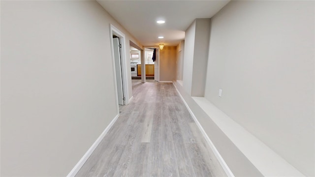 hallway featuring light wood-style flooring, baseboards, and recessed lighting