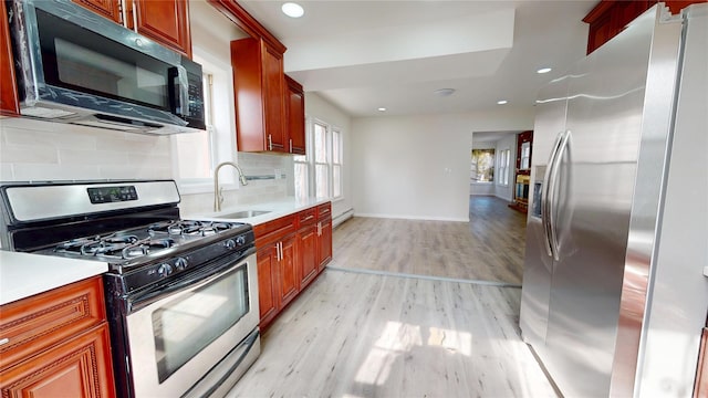 kitchen with a sink, light wood finished floors, stainless steel appliances, and light countertops