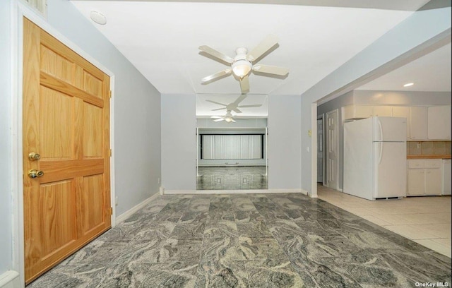 spare room featuring a ceiling fan, light tile patterned flooring, and baseboards