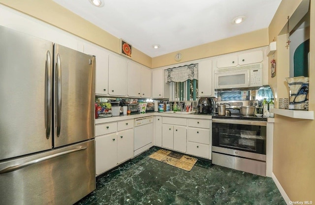 kitchen with dark floors, stainless steel appliances, light countertops, white cabinetry, and a sink