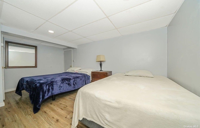 bedroom featuring a drop ceiling and wood finished floors