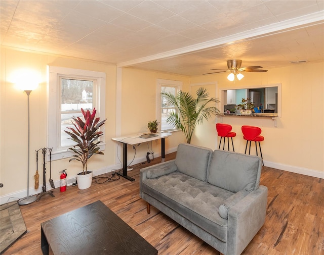 living area featuring wood finished floors, a ceiling fan, and baseboards