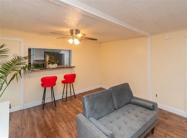 living area featuring ceiling fan, baseboards, and wood finished floors