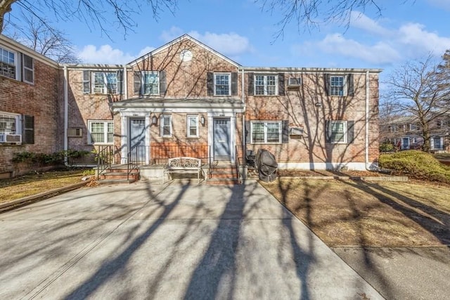 view of front of property with entry steps, cooling unit, and brick siding