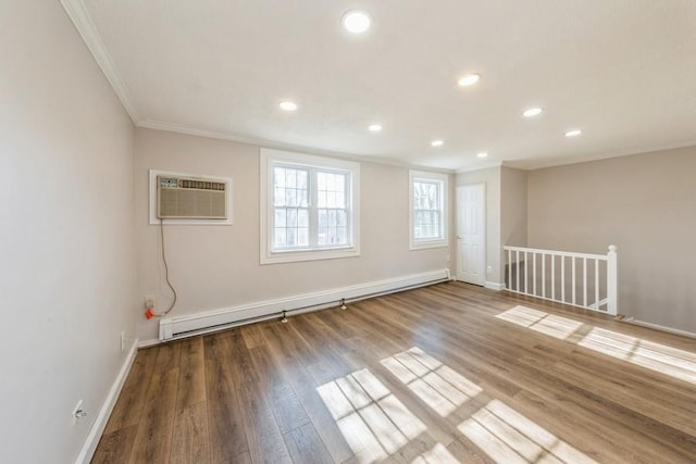 unfurnished room featuring a baseboard heating unit, a wall unit AC, wood finished floors, and crown molding